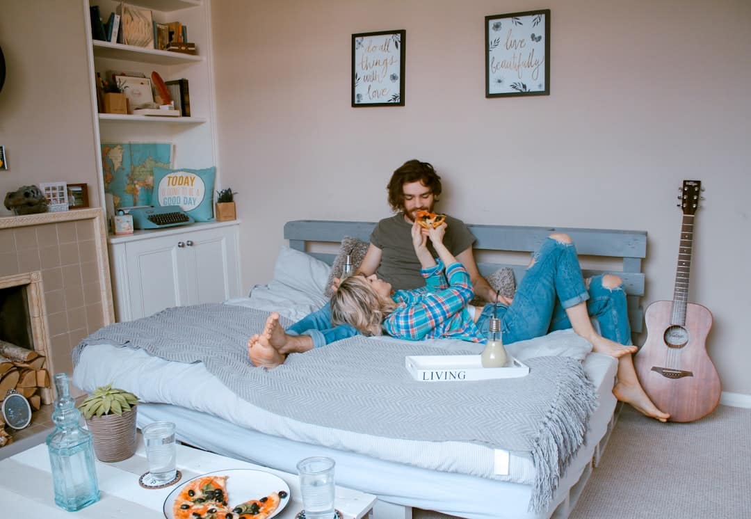 Aktivitäten für Zuhause als Paar Paar liegt im Bett und isst Pizza